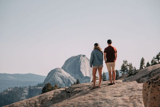A scenic view of a couple standing on a rock in Yosemite National park