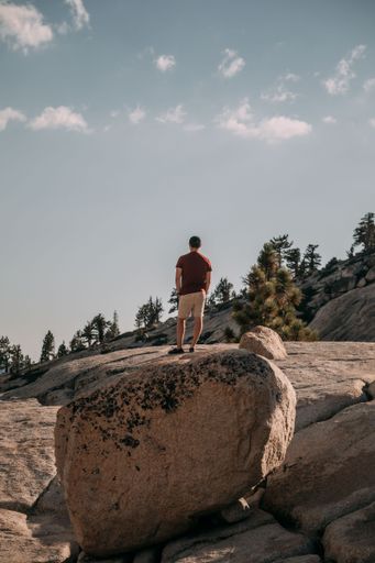 A scenic view of a male hiker standing on a rock at Joshua Tree National Park, California