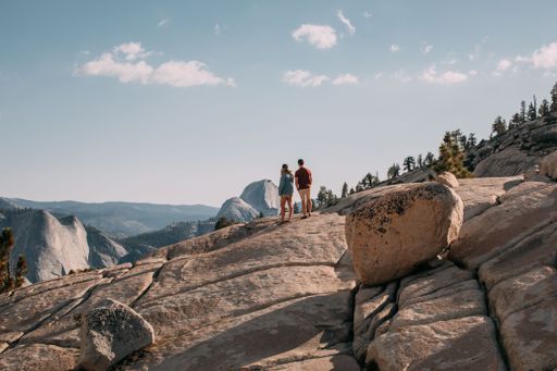 A scenic view of a couple standing on a rock in Yosemite National park