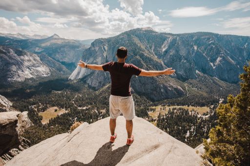 A scenic view of a male hiker standing on a rock at Joshua Tree National Park, California