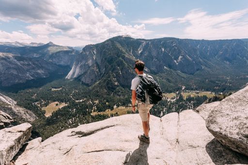 A scenic view of a male hiker standing on a rock at Joshua Tree National Park, California