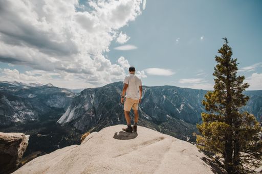 A scenic view of a male hiker standing on a rock at Joshua Tree National Park, California