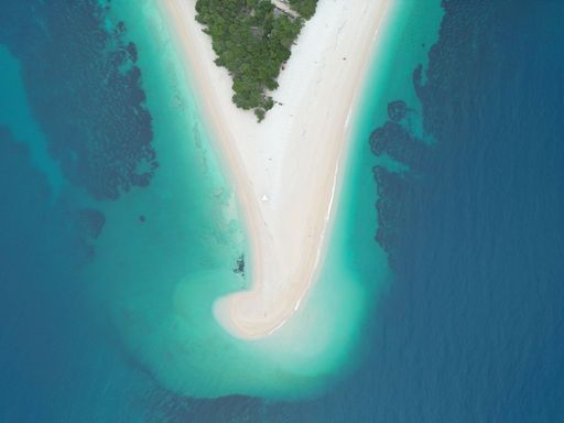 An aerial shot of a picturesque beach featuring powdery white sand and crystal blue waters