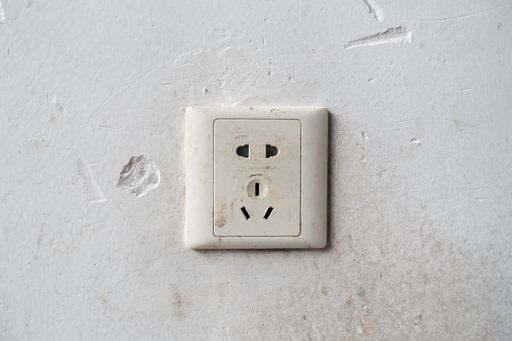 An old socket on a damaged white wall