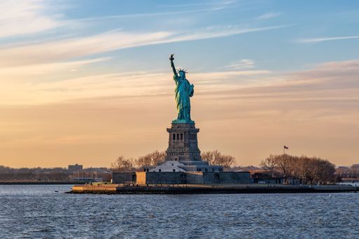 A breathtaking image of the iconic Statue of Liberty in New York City, USA, against a stunning sunset sky