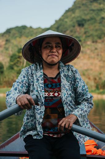 A Southeast Asian woman paddling a boat to Thien Tru Temple and the Perfume Pagoda in Hanoi, Vietnam