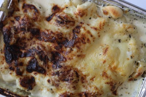 A closeup shot of an aluminium tray with gnocchi and cheese sauce