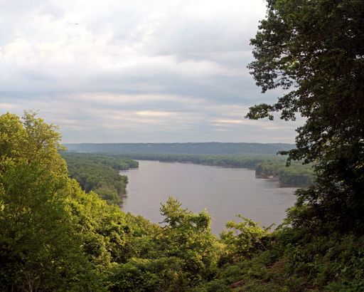 A high angle shot of a lake surrounded by beautiful greenery under a cloudy sky