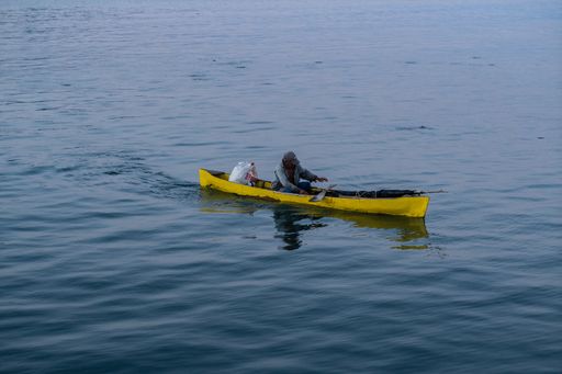 A person rowing a small yellow boat in the port of La Ceiba, Honduras