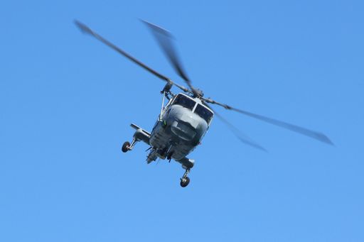 A closeup of a helicopter in mid-flight in the blue sky