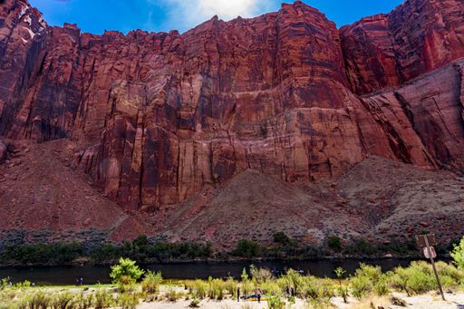 This image shows a view of Horseshoe Bend on the Colorado River from the river looking up to the observation point. People are visible up on the cliff