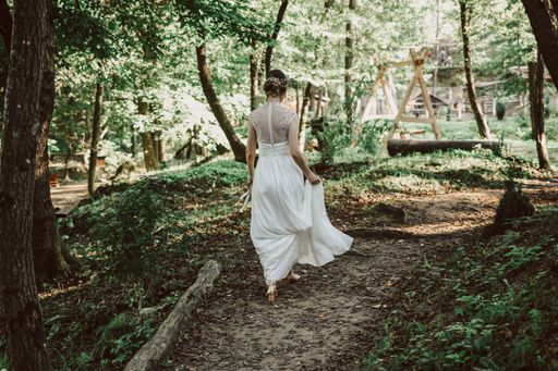 A rear view of a beautiful elegant bride walking in the garden