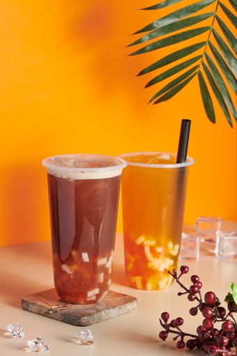 Two plastic cups filled with fresh and tasty orange and grapefruit juices on the table