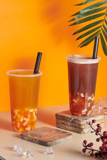 Two plastic cups filled with fresh and tasty orange and grapefruit juices on the table