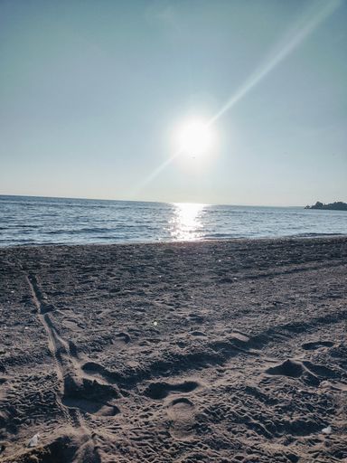 A beach of fine sand illuminated by the sun's rays, located near a tranquil ocean