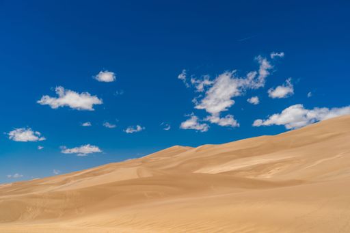 A scenic view of a vast desert landscape, featuring a rolling sand dune at Great Sand Dunes National Park