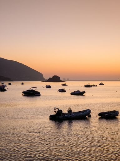 A scenic view of boats moored at the harbor of the sea at golden sunrise in Sesibra, Lisbon, Portugal