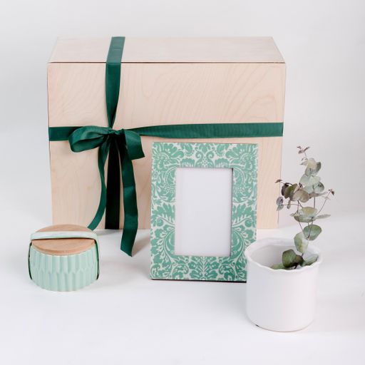A closeup shot of a gift set with a patterned picture frame, white flowerpot and green jewelry box