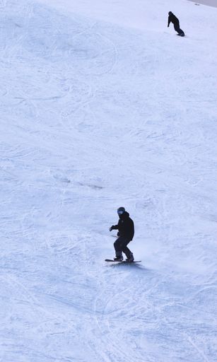 Two people enjoying the winter season outdoors, snowboarding on a snowy slope