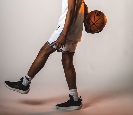 A photo of a basketball player throwing a behind the back pass. Photo taken on a white backdrop.