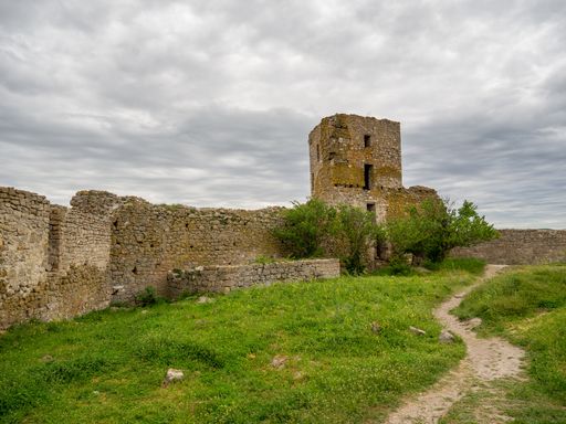 the Enisala fortress ruins in a green field under a cloudy sky in the Dobrogea region, Romania