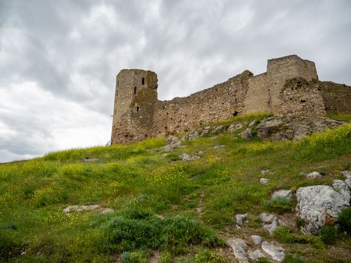 the Enisala fortress ruins in a green field under a cloudy sky in the Dobrogea region, Romania