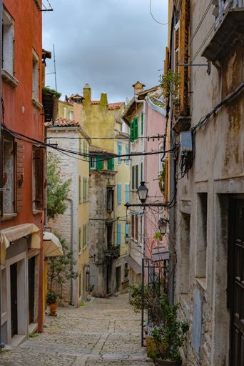 A vertical shot of a paved road in a narrow alley in Rovinj, Croatia with colorful buildings around