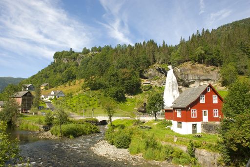 Waterfall Steinsdalsfossen near Bergen, Norway in beautiful nature next to red Scandinavian house