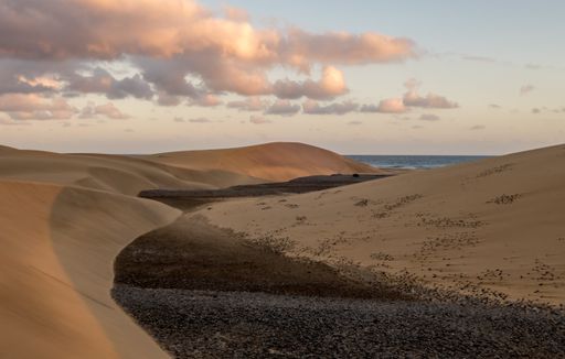 A wide angle shot of a desert under a sky full of clouds