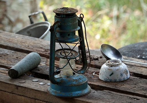An antique light lamp resting atop a wooden bench beside a metallic object.