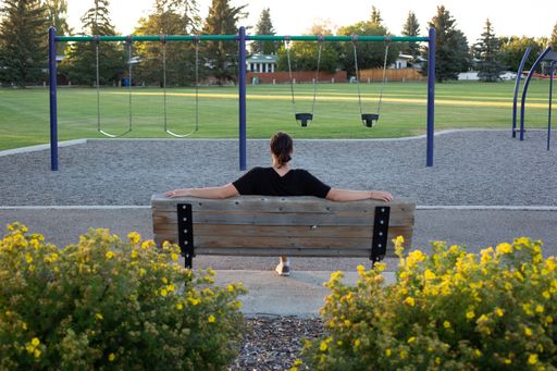 A closeup shot of a woman sitting on a bench on the playground
