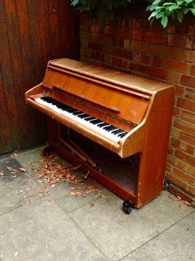 A vertical shot of an old wooden organ against a brick wall backgrou