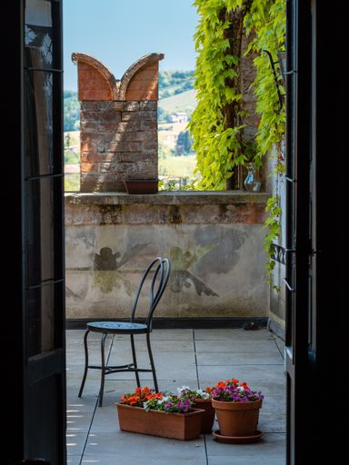 A vertical shot of a vintage garden chair and flower pots near the door