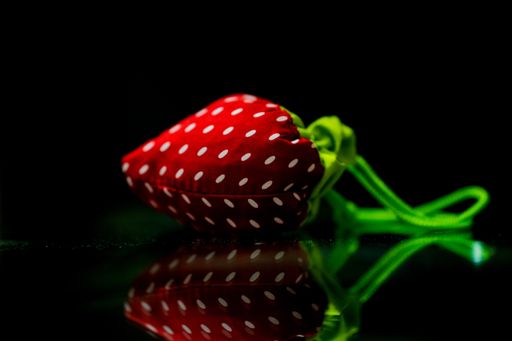 A strawberry-shaped fabric and its reflection isolated on the black backgrou
