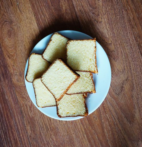 A top view shot of loaf bread slices on a white plate on a wooden table