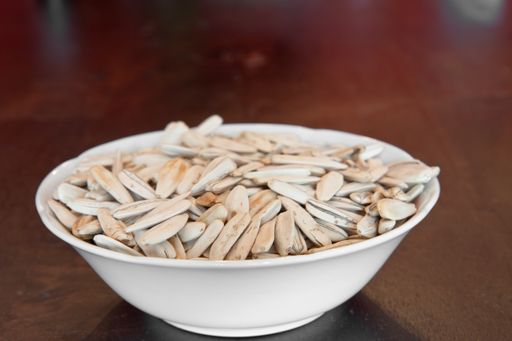 A bowl of white sunflower seeds on a wooden table