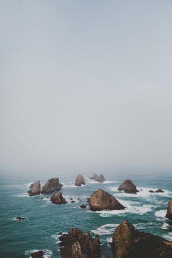 A vertical shot of large rocks in nugget point ahuriri, new zealand with a foggy background