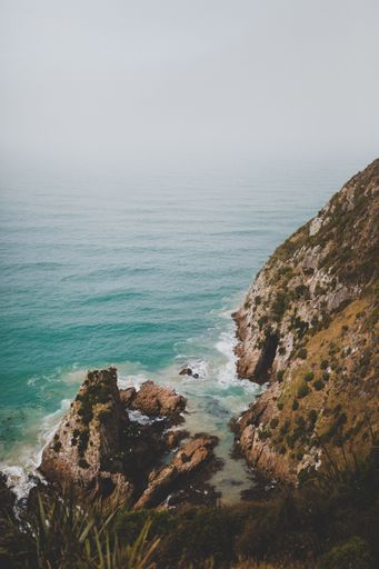 A vertical shot of large rocks in nugget point ahuriri, new zealand with a foggy background