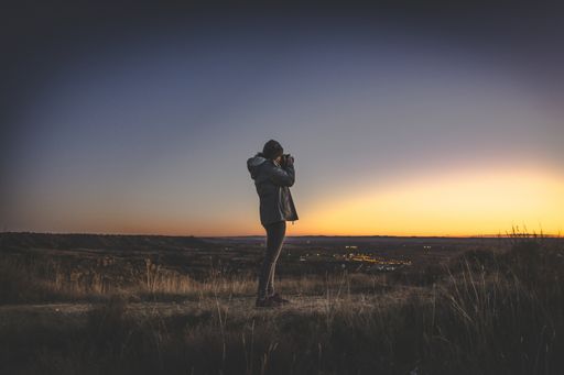 A young girl taking pictures during sunset on the mountain