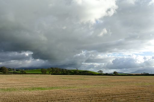 A dry grassy field under a cloudy sky in the countryside of Wales