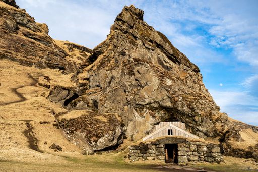 A small cave nestled into a rocky cliff face, situated in a natural landscape