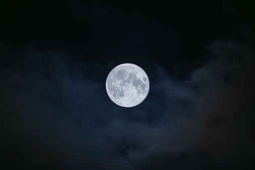 A stunning shot of a full moon in a dark night sky, illuminated against the inky darkness