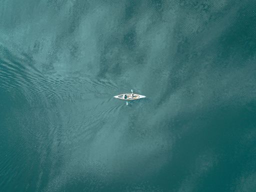 An aerial view of a white motorboat traveling across a scenic lake.