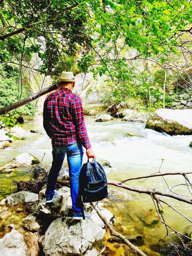 hiker with hat and backpack in hand looks at the Alento river in Abruzzo, Italy