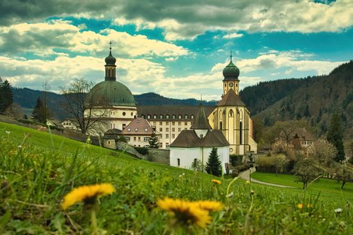 The Saint Trudpert's Abbey on a hill covered in greenery under the sunlight in Munstertal, Germany