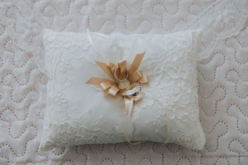 An elegant ring pillow featuring white linen fabric and a single flower for decoration