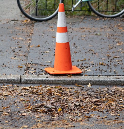 An orange traffic cone is prominently featured in the foreground, situated on the side of a road
