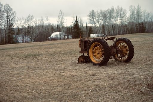 A closeup shot of an old agricultural machine with yellow wheels in the field