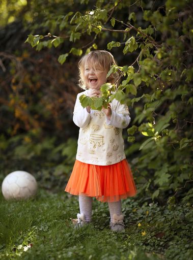 An adorable Caucasian little girl playing outdoors and laughing