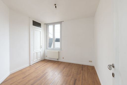 An interior shot of an empty room featuring hardwood floors and wood floors, with large windows